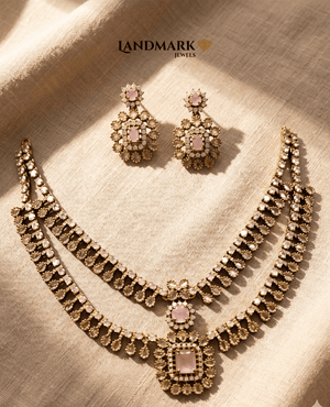 Double-layered antique gold necklace set featuring rose pink rectangular stones and Polki-style crystal embellishments with matching floral drop earrings by Landmark Jewels.