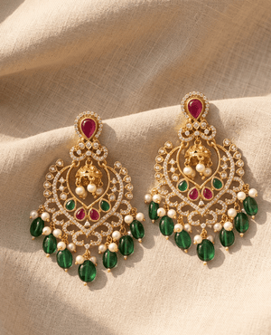 Heavy statement chandelier earrings in gold by Landmark Jewels featuring intricate crystal work, red and green stone accents, and a lush fringe of smooth emerald-green elongated beads and pearls.