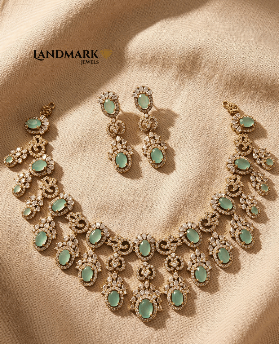 landmark-jewels-imitation-jewelry-set-featuring-a-gold-toned-necklace-and-earrings-with-oval-mint-green-stones-and-white-crystal-embellishments-on-a-beige-fabric-background