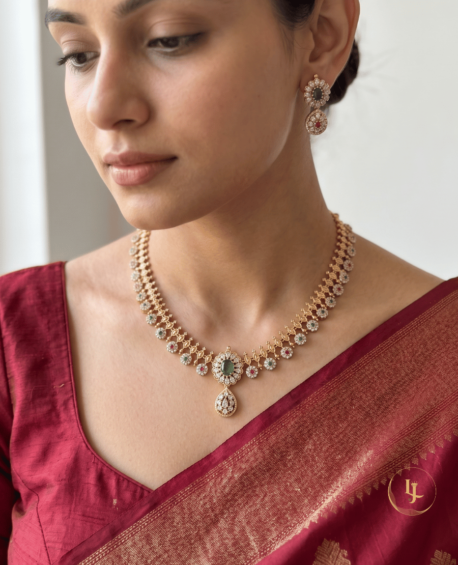 model-showcasing-a-traditional-emerald-and-ruby-floral-necklace-set-with-matching-earrings-by-landmark-jewels-styled-with-a-maroon-saree
