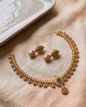 High-angle flat lay of the Emerald & Ruby Duo necklace and earring set on a neutral fabric background, highlighting the craftsmanship of Landmark Jewels.