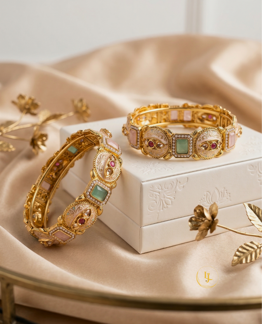pair-of-gold-plated-indian-meenakari-bangles-with-ruby-and-emerald-stones-on-a-beige-fabric-background