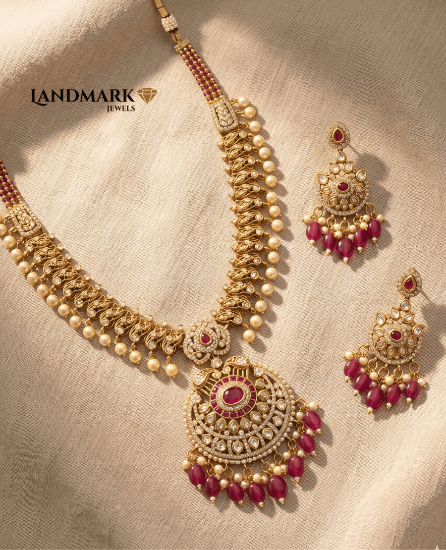 landmark-jewels-antique-gold-plated-necklace-featuring-ruby-stones-pearl-droplets-and-matching-heavy-chandelier-earrings-on-a-beige-fabric-background