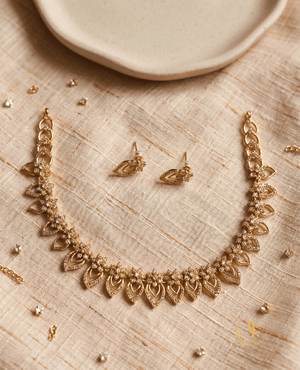 Overhead shot of the complete Landmark Jewels jewelry set including the necklace and earrings laid out on a textured cream fabric background.