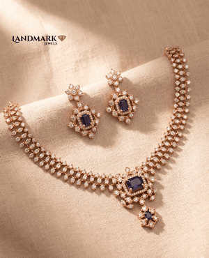 Landmark Jewels Ruby Red and American Diamond studded imitation necklace with matching drop earrings on a beige fabric background.