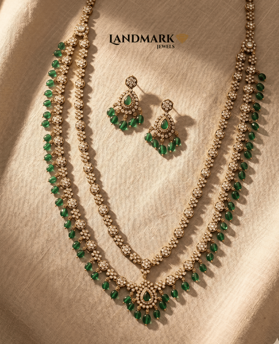 landmark-jewels-antique-gold-plated-double-layer-long-necklace-and-earring-set-featuring-white-polki-stones-and-emerald-green-bead-droplets-on-a-beige-fabric-background