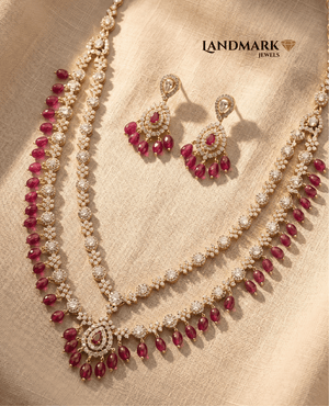 Landmark Jewels gold-plated dual-layer necklace with white Polki stones and ruby red teardrop beads, featuring matching earrings.