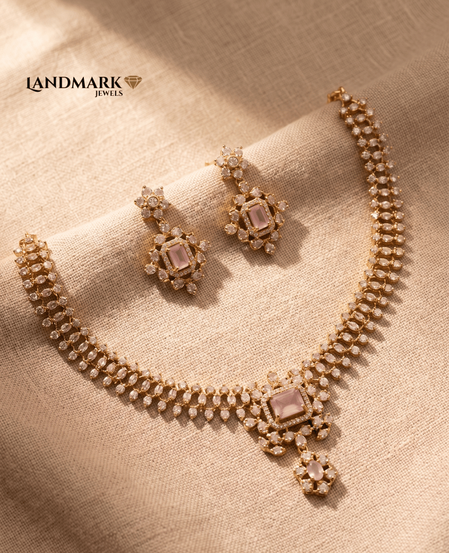 gold-plated-necklace-set-by-landmark-jewels-featuring-double-row-cubic-zirconia-and-emerald-cut-pink-stones-with-matching-drop-earrings-on-a-neutral-fabric-background