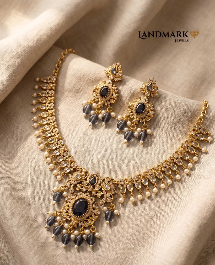 landmark-jewels-antique-gold-plated-necklace-and-earring-set-featuring-deep-blue-gemstones-white-pearls-and-intricate-floral-metalwork-on-a-beige-fabric-background