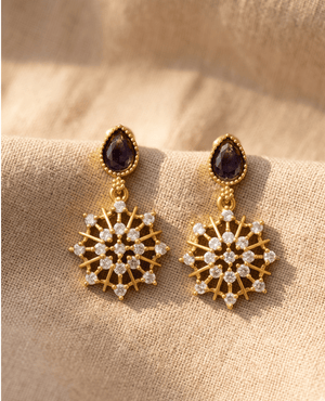 Landmark Jewels gold-finished dangle earrings featuring dark purple amethyst-colored teardrop stones and clear CZ crystal starburst pendants.