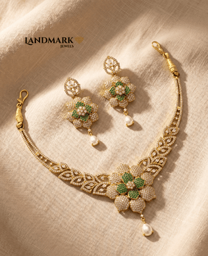 A gold-toned necklace and earring set featuring green and white floral stone designs with hanging pearl drops by Landmark Jewels.