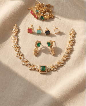 Gold leaf-pattern necklace with a central green stone, matching earrings, and an assortment of interchangeable colored stud stones above it