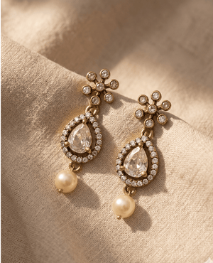 Landmark Jewels vintage-style gold earrings with a small star-floral stud, a large teardrop crystal charm with a pave border, and a dangling round ivory pearl.