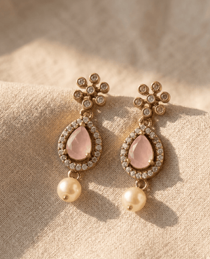 A pair of antique gold-plated drop earrings featuring a faceted light pink stone in a crystal-halo teardrop frame, finished with a classic white pearl dangle underneath.