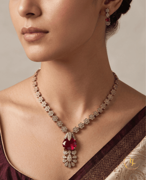Close-up of a model wearing the Landmark Jewels ruby red floral necklace and matching earrings with a maroon silk saree.