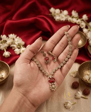 Landmark Jewels ruby red necklace and earring set held in hand to show scale and intricate craftsmanship