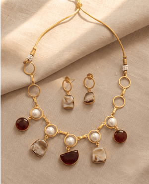 Gold link necklace featuring hanging white pearls, sparkling Monalisa stones in warm tones, and rich wine-colored gemstone drops, with matching drop earrings.