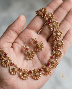 Handheld view showing the detailed craftsmanship and scale of the matte gold fan-style necklace and matching earrings.