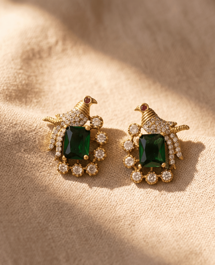 pair-of-gold-plated-bird-themed-stud-earrings-by-landmark-jewels-featuring-a-crystal-studded-bird-with-a-red-eye-accent-clutching-a-large-rectangular-emerald-cut-green-stone