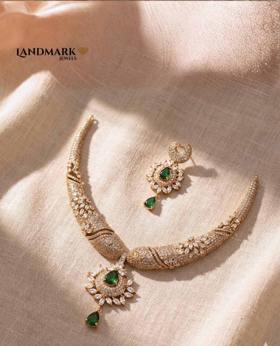 landmark-jewels-gold-plated-necklace-and-earring-set-featuring-emerald-green-teardrop-stones-and-intricate-white-cubic-zirconia-floral-patterns-on-a-neutral-fabric-background