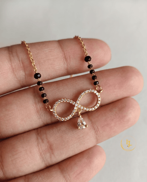 Landmark Jewels gold-plated mangalsutra featuring an infinity-shaped pendant with American Diamonds and a hanging pear-cut stone on a designer black bead chain.