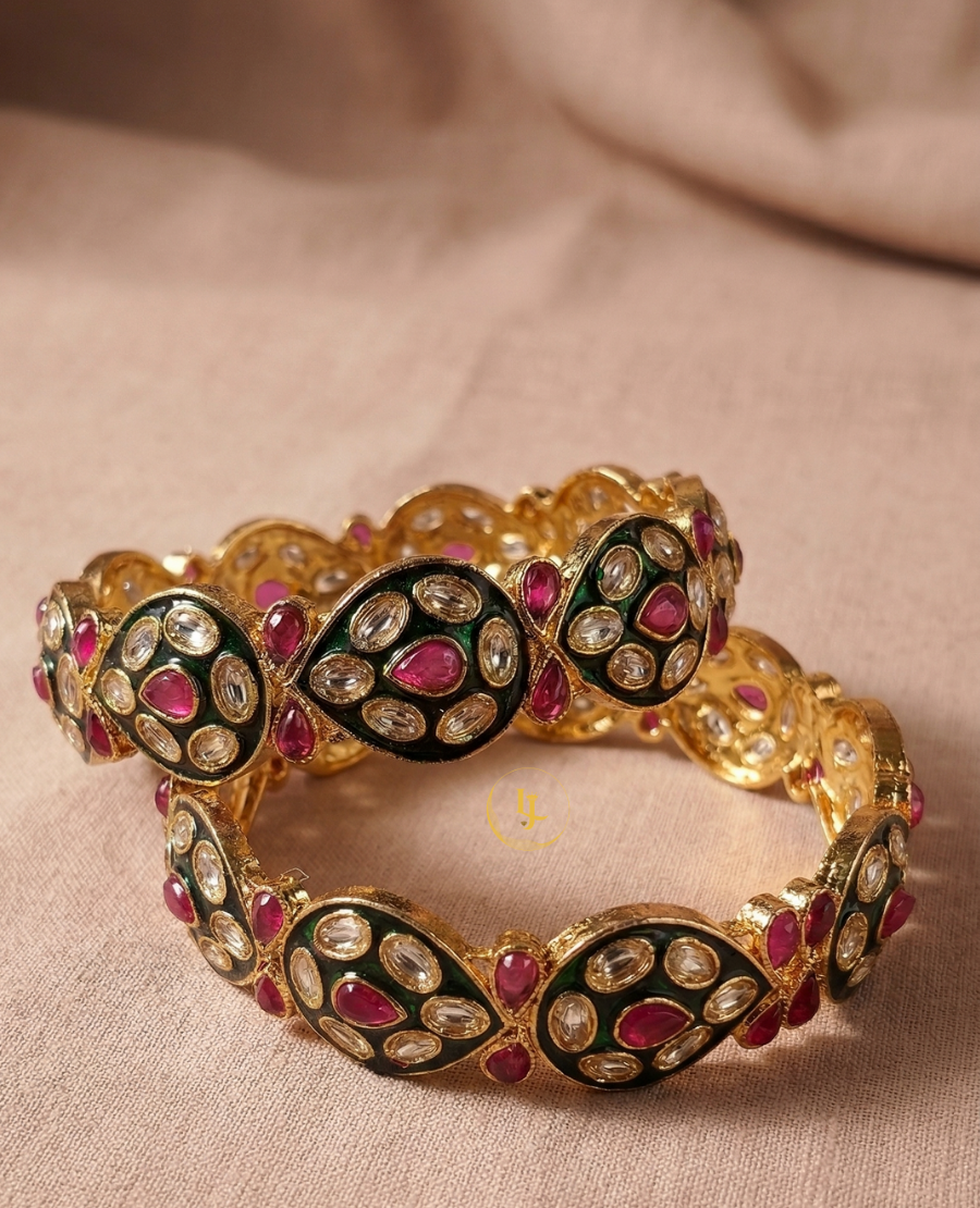 pair-of-gold-plated-indian-bangles-with-ruby-stones-white-polki-crystals-and-black-enamel-work-on-a-floral-background