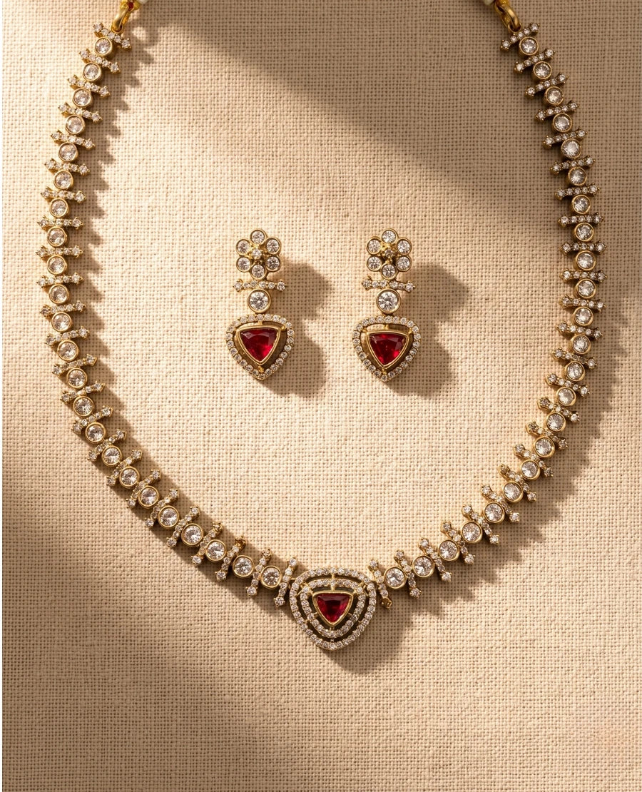 gold-plated-ruby-red-triangular-cz-stone-necklace-set-with-matching-earrings-on-beige-fabric