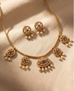 Gold plated temple necklace set with purple stones pearl drops and matching earrings on woven chain