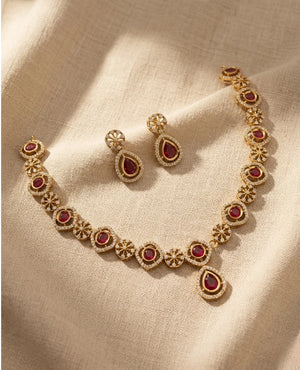 Gold finish ruby red CZ necklace set with floral motifs and matching teardrop earrings